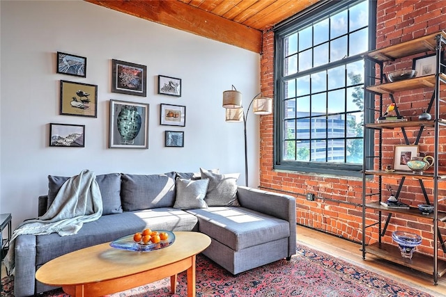 living room featuring brick wall, beamed ceiling, wood finished floors, and wood ceiling