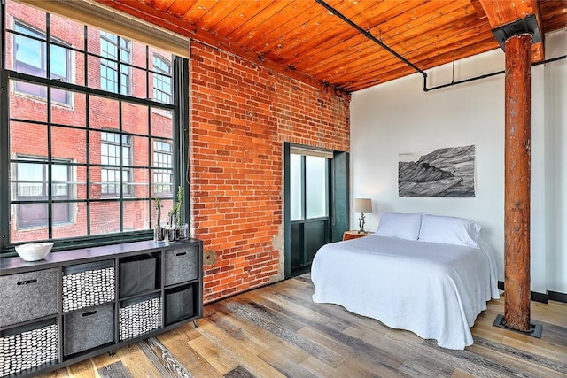 bedroom featuring wooden ceiling, brick wall, and wood finished floors