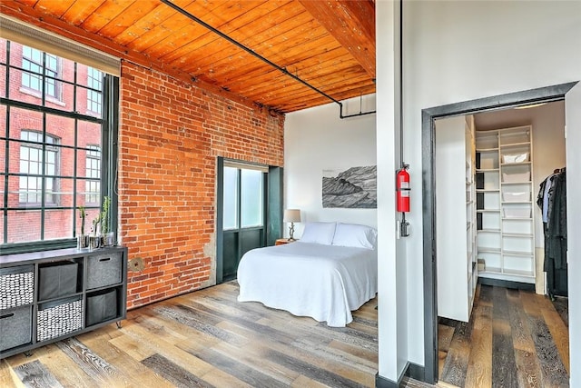 bedroom with a closet, wood ceiling, brick wall, multiple windows, and hardwood / wood-style flooring