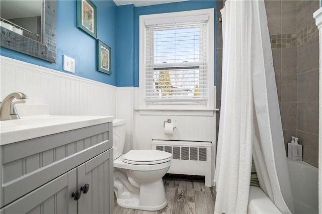 full bath featuring radiator, a wainscoted wall, toilet, wood finished floors, and vanity