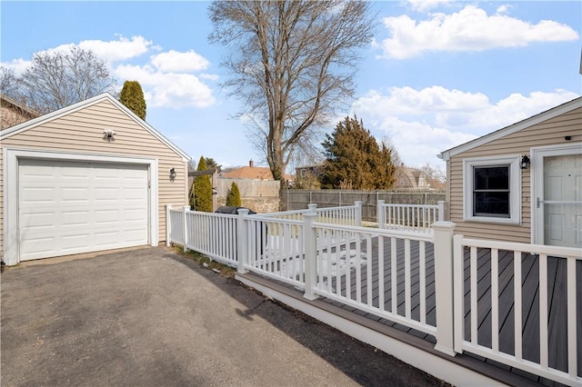 exterior space with a garage, driveway, an outbuilding, fence, and a wooden deck