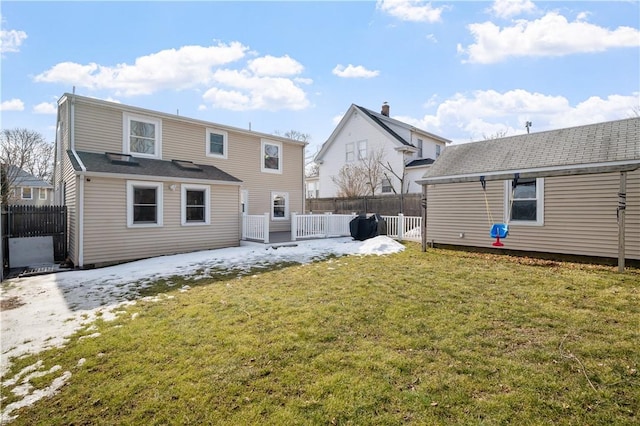 rear view of house with fence and a lawn