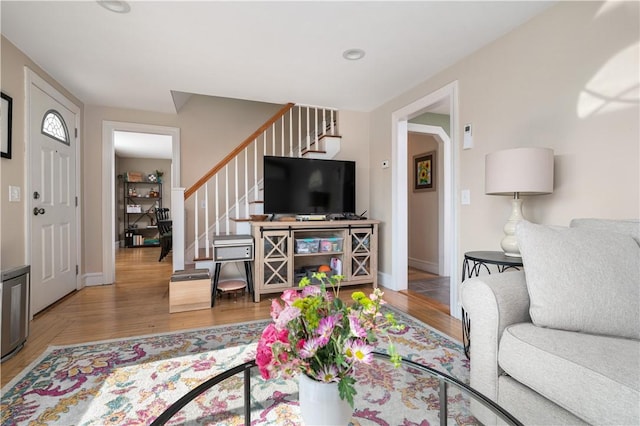 living area with baseboards, stairway, and wood finished floors