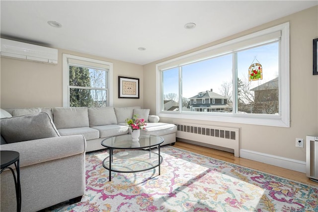 living room with radiator, a healthy amount of sunlight, a wall unit AC, and wood finished floors