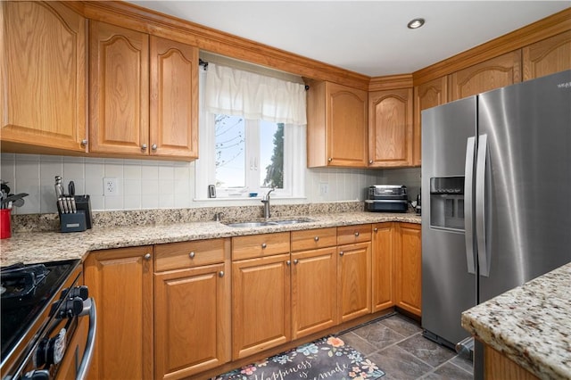 kitchen with brown cabinets, a sink, light stone countertops, stainless steel appliances, and backsplash