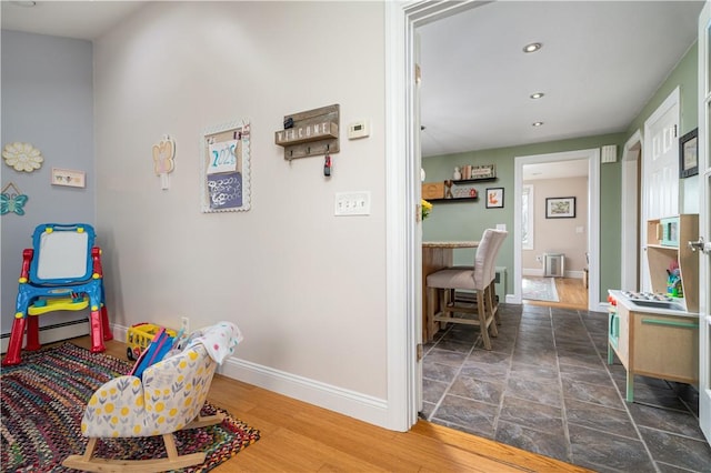 game room featuring a baseboard radiator, baseboards, wood finished floors, and recessed lighting