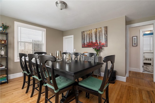 dining room featuring baseboards, light wood-style flooring, and radiator heating unit