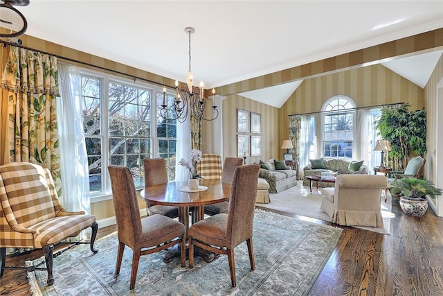 dining room with ornamental molding, wood finished floors, a chandelier, baseboards, and wallpapered walls