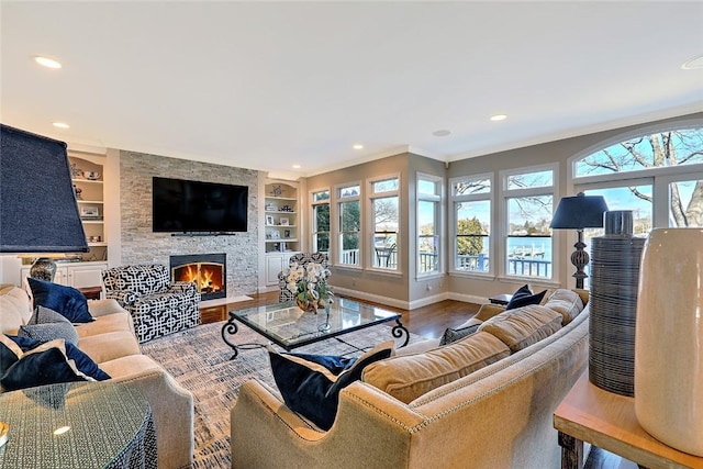 living room with a stone fireplace, recessed lighting, wood finished floors, baseboards, and built in features