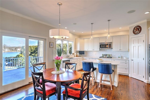 dining area featuring a water view, dark wood-style floors, crown molding, and recessed lighting