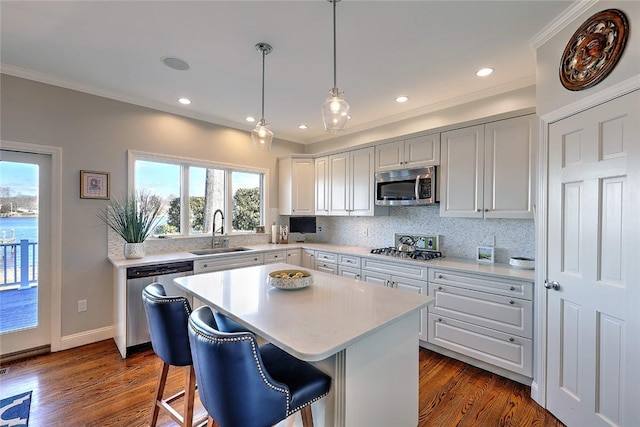 kitchen with crown molding, stainless steel appliances, light countertops, backsplash, and a sink