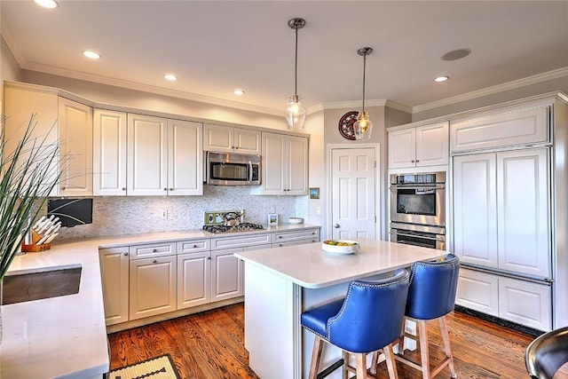 kitchen with dark wood-style flooring, a kitchen island, light countertops, appliances with stainless steel finishes, and decorative backsplash