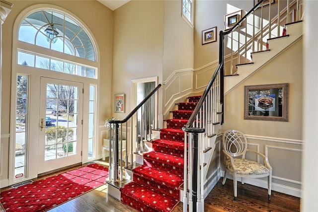 entryway featuring a wainscoted wall, a high ceiling, a decorative wall, and wood finished floors