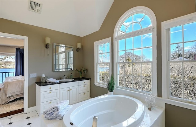 full bathroom featuring connected bathroom, vanity, visible vents, vaulted ceiling, and a bath