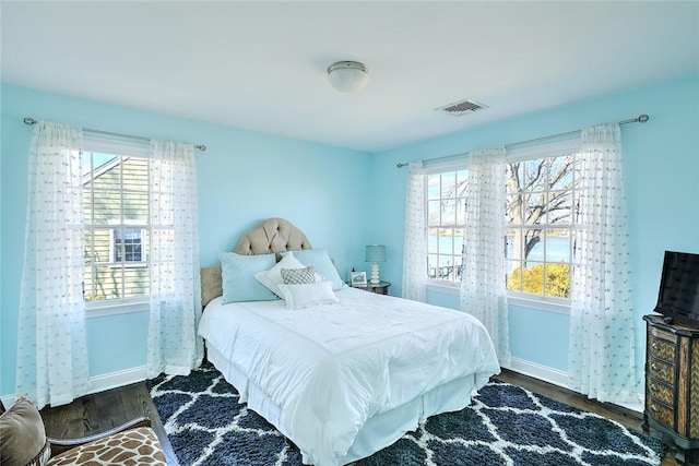 bedroom featuring dark wood-style flooring, visible vents, baseboards, and multiple windows