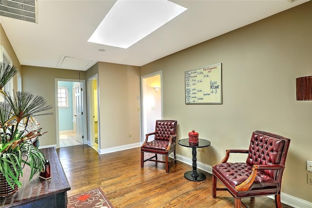 living area with baseboards, wood finished floors, visible vents, and attic access