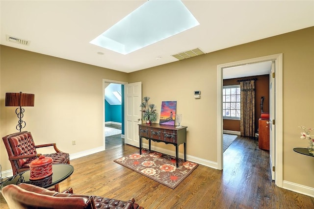 sitting room featuring a skylight, visible vents, and wood finished floors