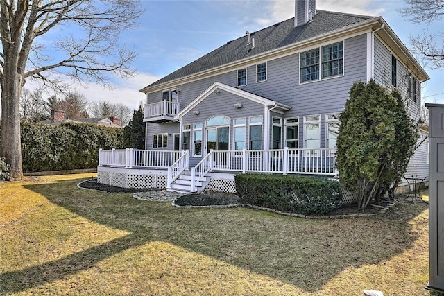 back of property featuring a yard, a chimney, and a balcony