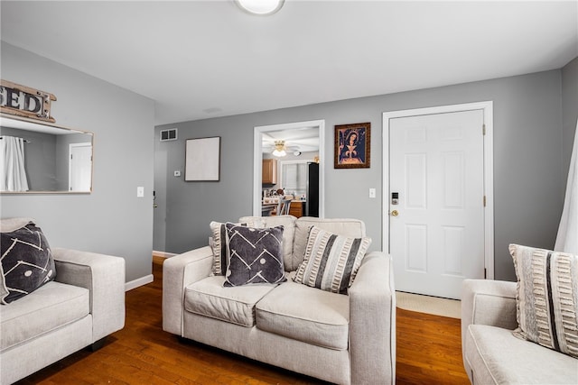 living room with visible vents, baseboards, and wood finished floors