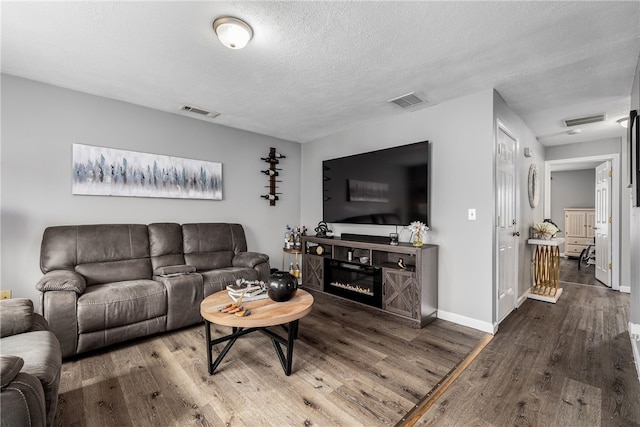 living area with visible vents and wood finished floors