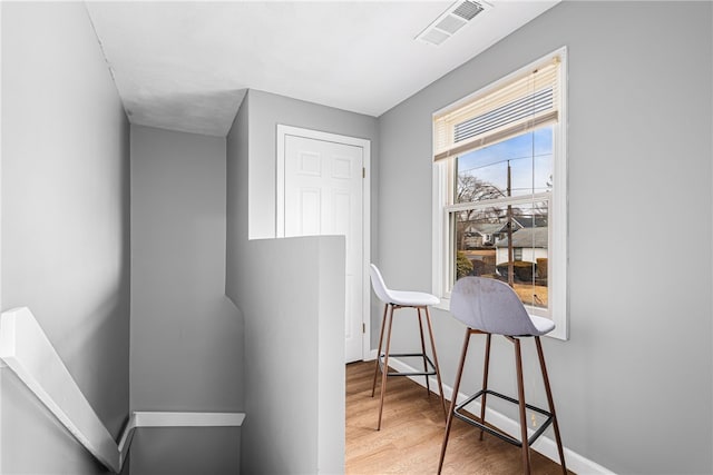 hallway featuring baseboards, visible vents, and wood finished floors