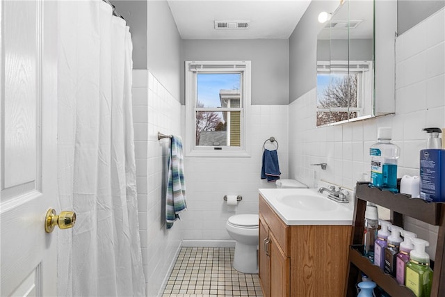 full bath featuring tile walls, visible vents, toilet, vanity, and tile patterned flooring