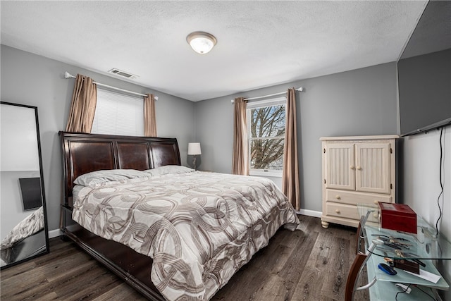 bedroom featuring visible vents, dark wood finished floors, a textured ceiling, and baseboards