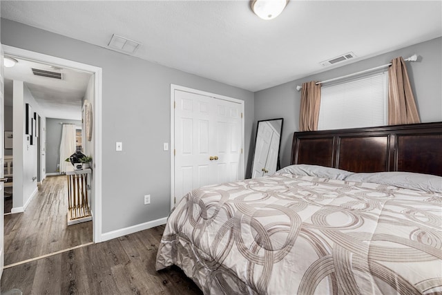 bedroom with baseboards, visible vents, and wood finished floors