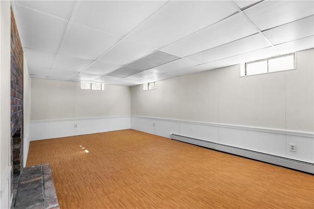 below grade area with a baseboard heating unit and a paneled ceiling