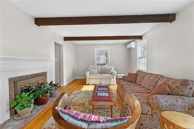 living room with wood finished floors, baseboards, a brick fireplace, beam ceiling, and a wall mounted air conditioner