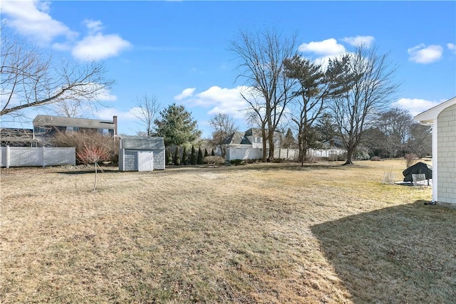 view of yard with a storage shed, fence, and an outbuilding