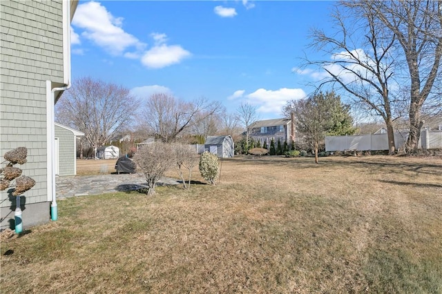 view of yard with an outbuilding, fence, and a storage shed