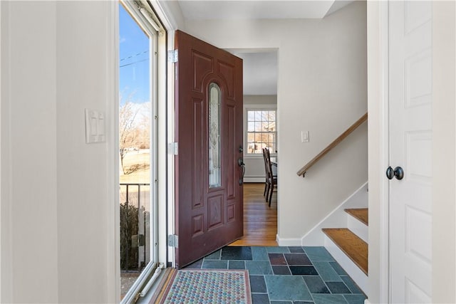 foyer with a baseboard heating unit, stairway, and baseboards