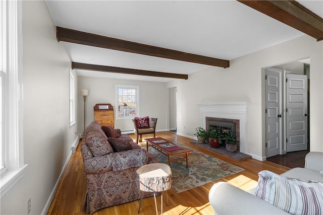 living room featuring beam ceiling, a fireplace, baseboards, and wood finished floors