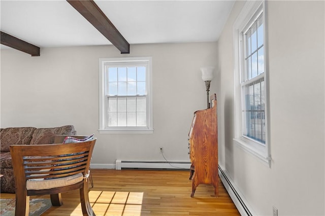 living area with a baseboard heating unit, wood finished floors, and beam ceiling