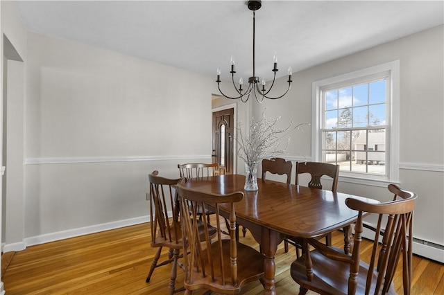 dining area featuring a chandelier, wood finished floors, and baseboards