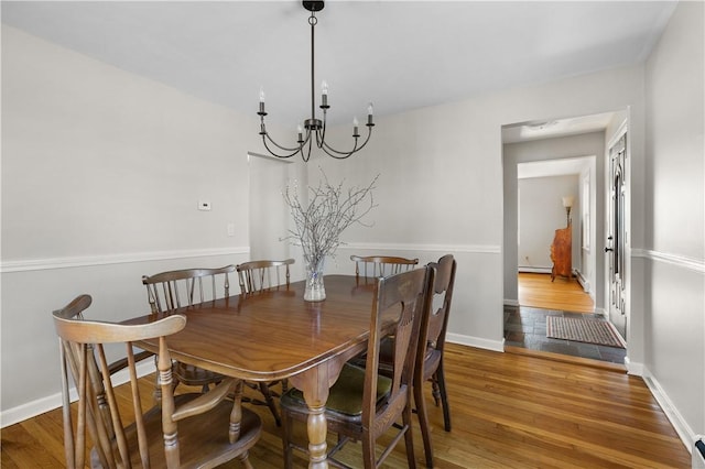 dining area with baseboards, a baseboard heating unit, wood finished floors, and an inviting chandelier