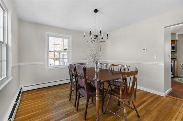 dining room with baseboards, a notable chandelier, a baseboard heating unit, and hardwood / wood-style floors