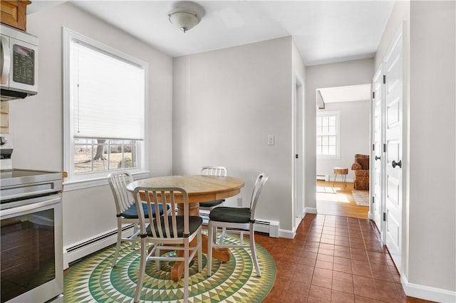 tiled dining room featuring baseboards, a baseboard heating unit, baseboard heating, and a wealth of natural light