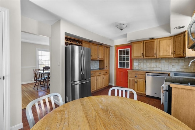 kitchen featuring baseboards, dark wood-style floors, backsplash, stainless steel appliances, and a sink