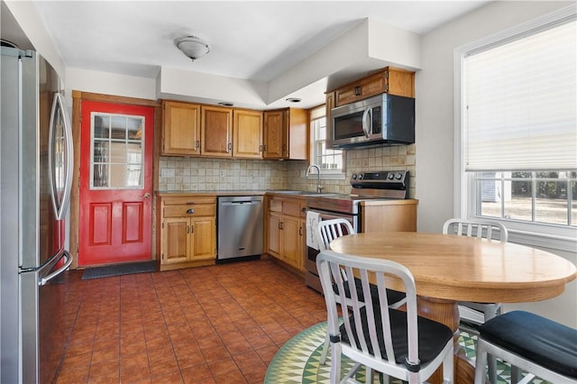 kitchen with stainless steel appliances, brown cabinets, a sink, and decorative backsplash