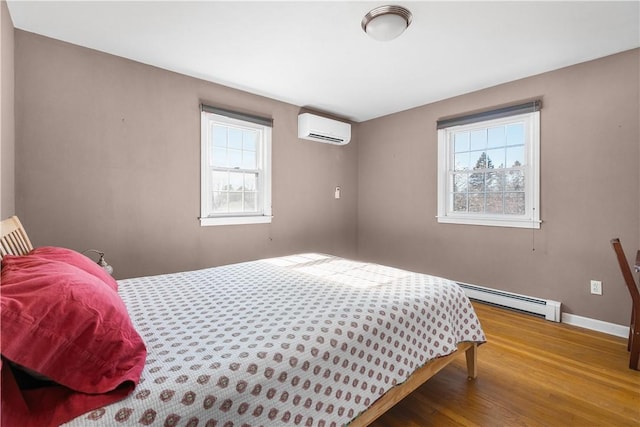 bedroom with a baseboard radiator, multiple windows, an AC wall unit, and wood finished floors