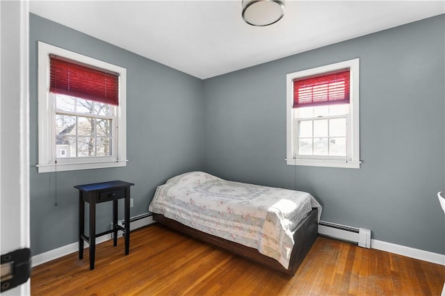 bedroom with a baseboard heating unit, baseboards, and wood finished floors