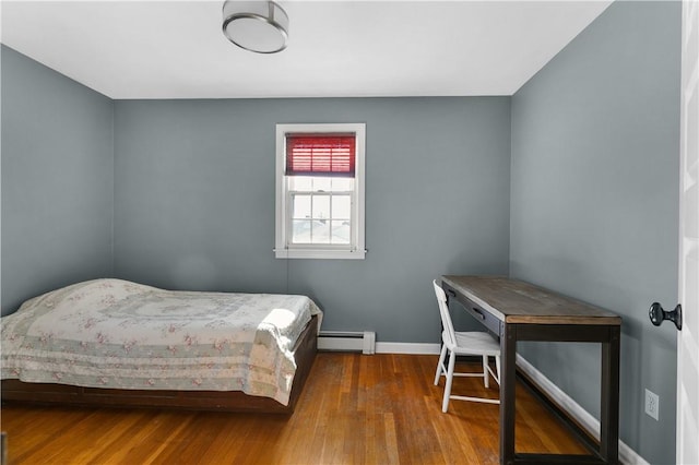 bedroom with a baseboard radiator, baseboards, and wood finished floors