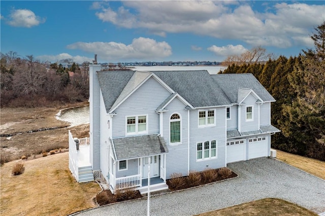 view of front facade with gravel driveway, a chimney, a porch, a front yard, and a garage