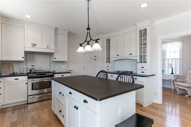 kitchen featuring dark countertops, white cabinets, a kitchen island, and stainless steel gas range oven