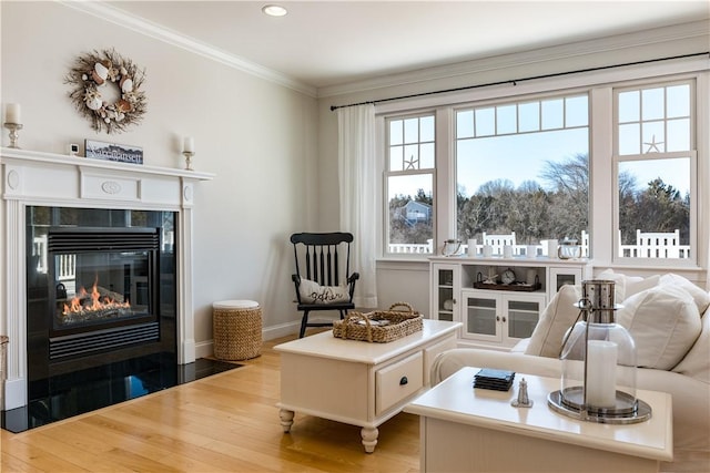 sitting room featuring ornamental molding, a fireplace, baseboards, and wood finished floors