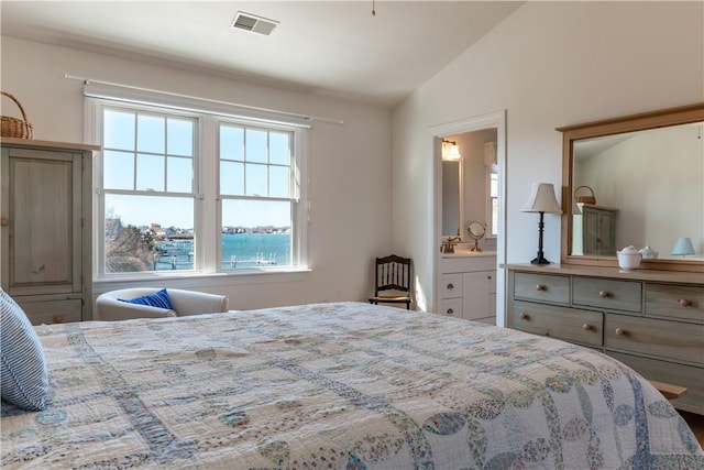 bedroom featuring lofted ceiling, visible vents, and ensuite bathroom