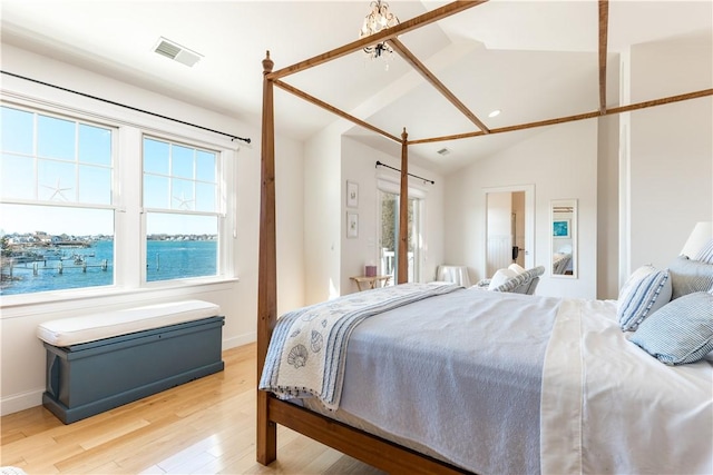 bedroom featuring light wood-style floors, baseboards, visible vents, and vaulted ceiling