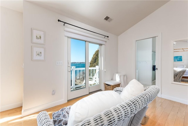 bedroom with light wood-style flooring, visible vents, baseboards, vaulted ceiling, and access to exterior